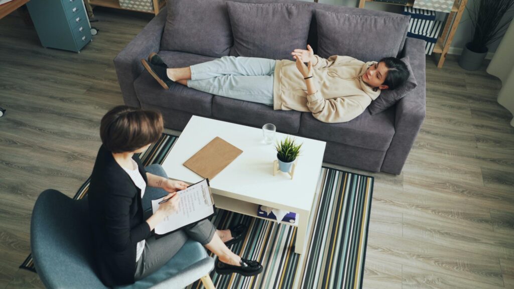 A psychotherapy session with a therapist consulting a client indoors on a sofa.