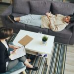 A psychotherapy session with a therapist consulting a client indoors on a sofa.